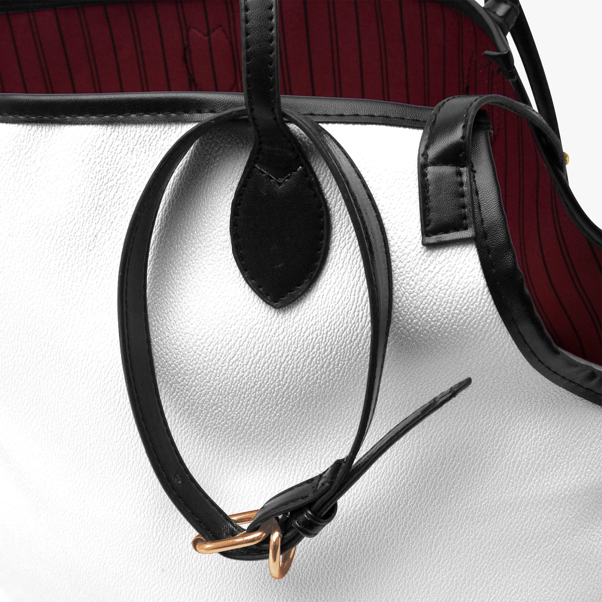 Close-up of the pet tote's black handle and strap, white faux leather and burgundy lining.