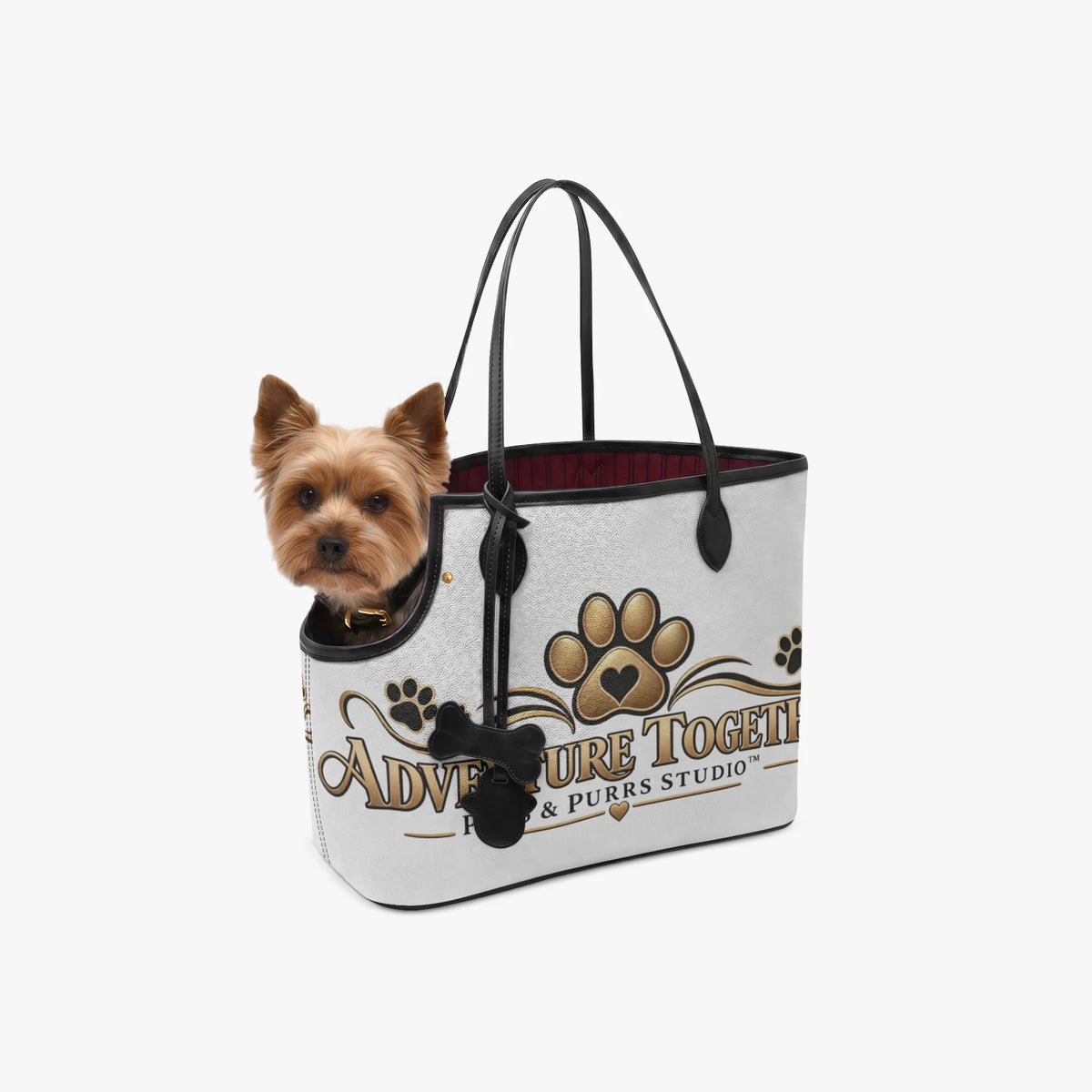 Small dog peeking out of the Adventure Together pet carrier tote with gold paw artwork and black handles.