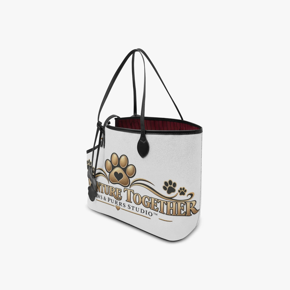 Angled front view of the Adventure Together pet tote showing gold artwork, black handles and burgundy lining.